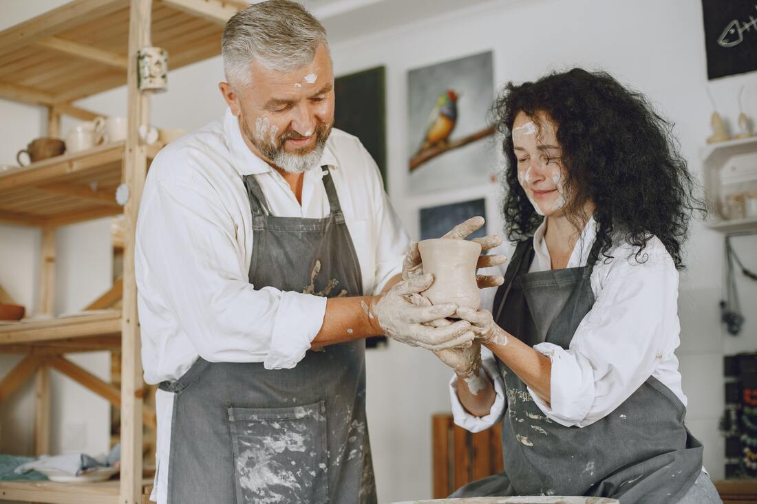 Old man with young woman molding a clay pot